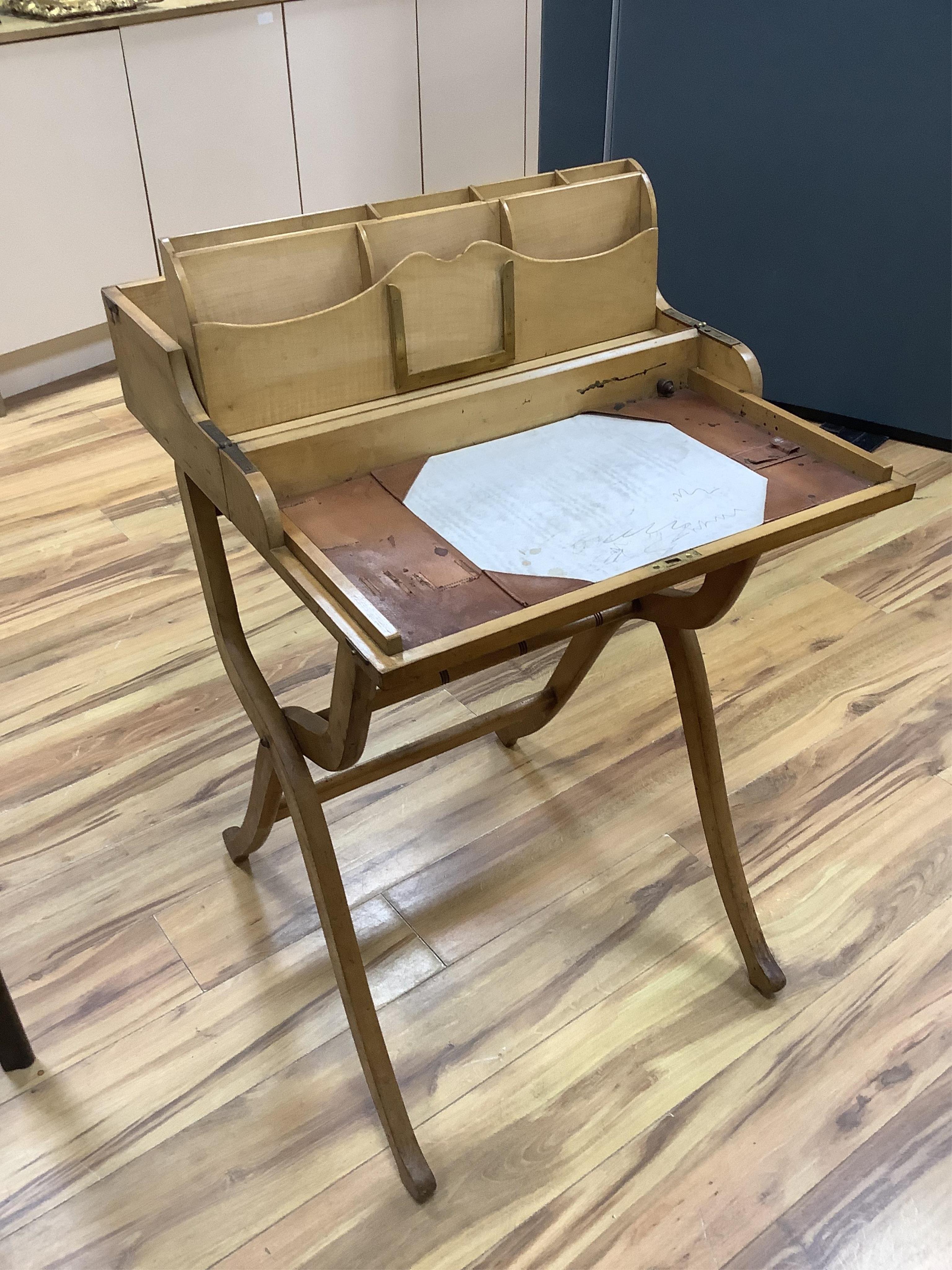 A late 19th century sycamore military folding campaign desk, raised on a trestle stand with X shaped supports, desk section with leather writing surface and folding letter rack, 93cm high, 56cm wide when folded. Conditio